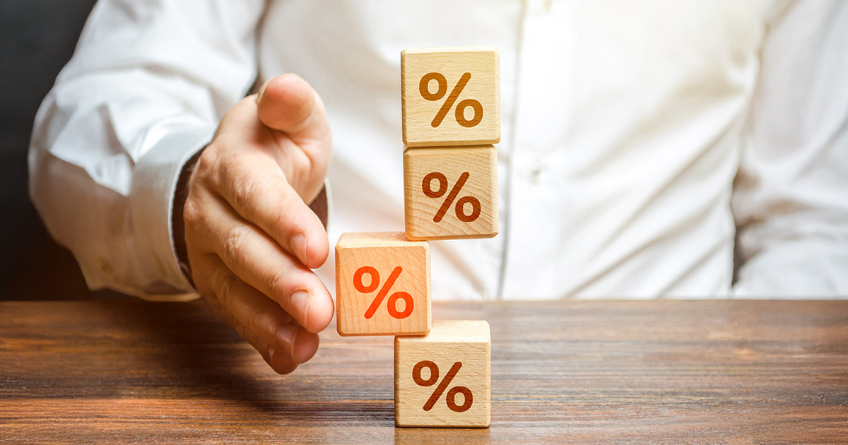 Una mano che stabilizza una pila di cubi di legno con il simbolo della percentuale, rappresentando il reintegro delle anticipazioni in Fopen.