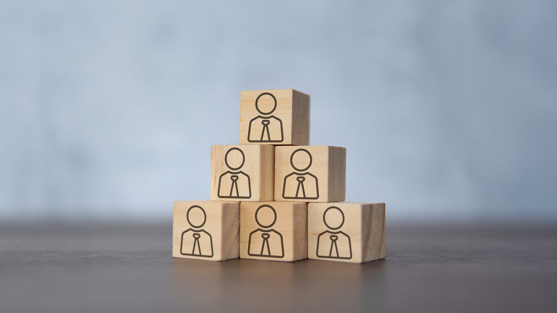 Una piramide composta da sei blocchi di legno, ciascuno con l'icona di una persona con cravatta, che simboleggia la struttura di leadership e l'organizzazione del Fondo Fopen