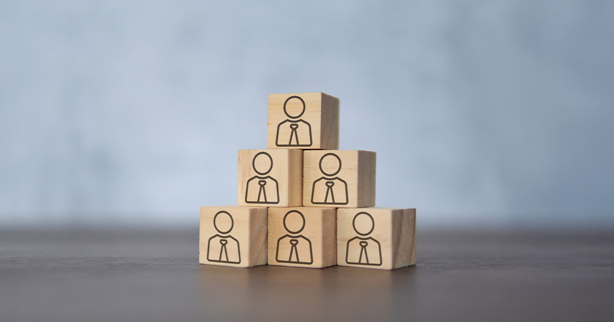 Una piramide composta da sei blocchi di legno, ciascuno con l'icona di una persona con cravatta, che simboleggia la struttura di leadership e l'organizzazione del Fondo Fopen