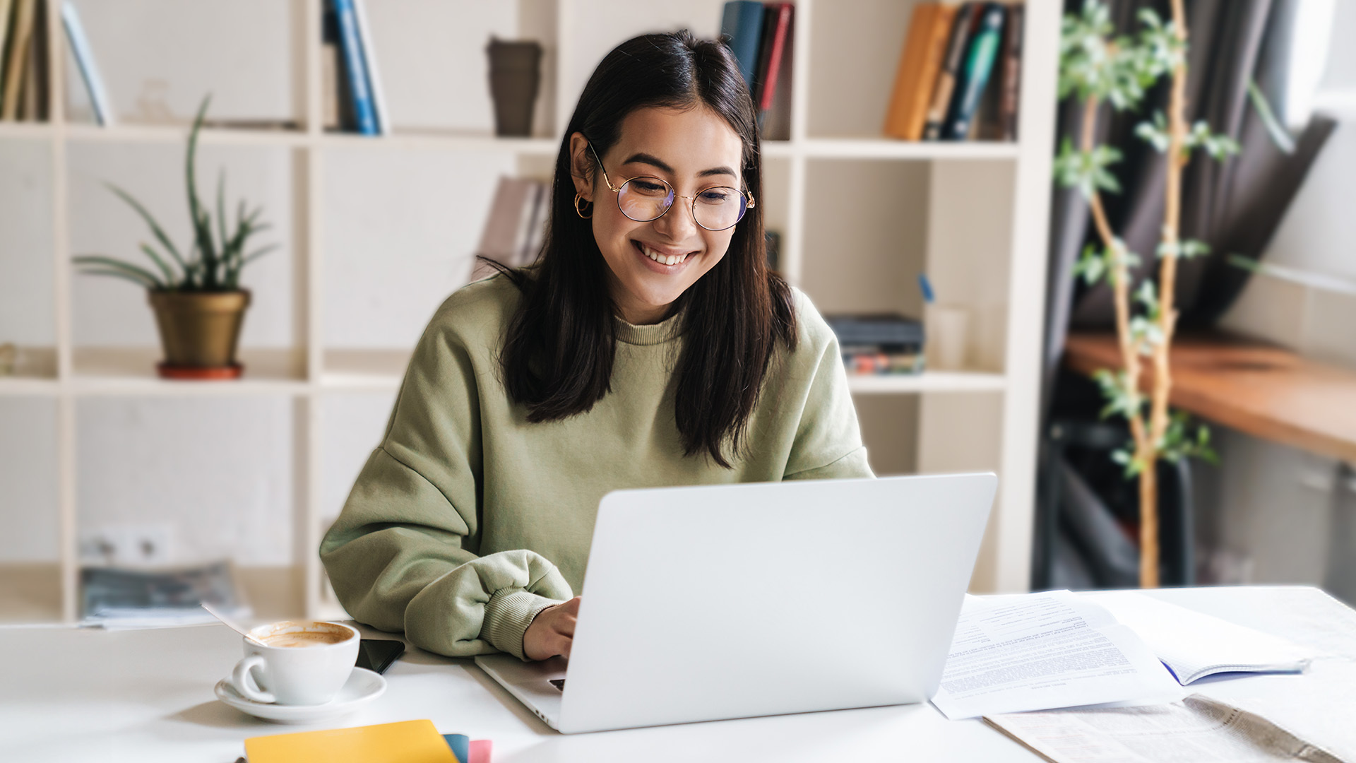 Una ragazza sorridente che lavora al computer, pronta ad aderire da giovani a Fopen per costruire il proprio futuro previdenziale.