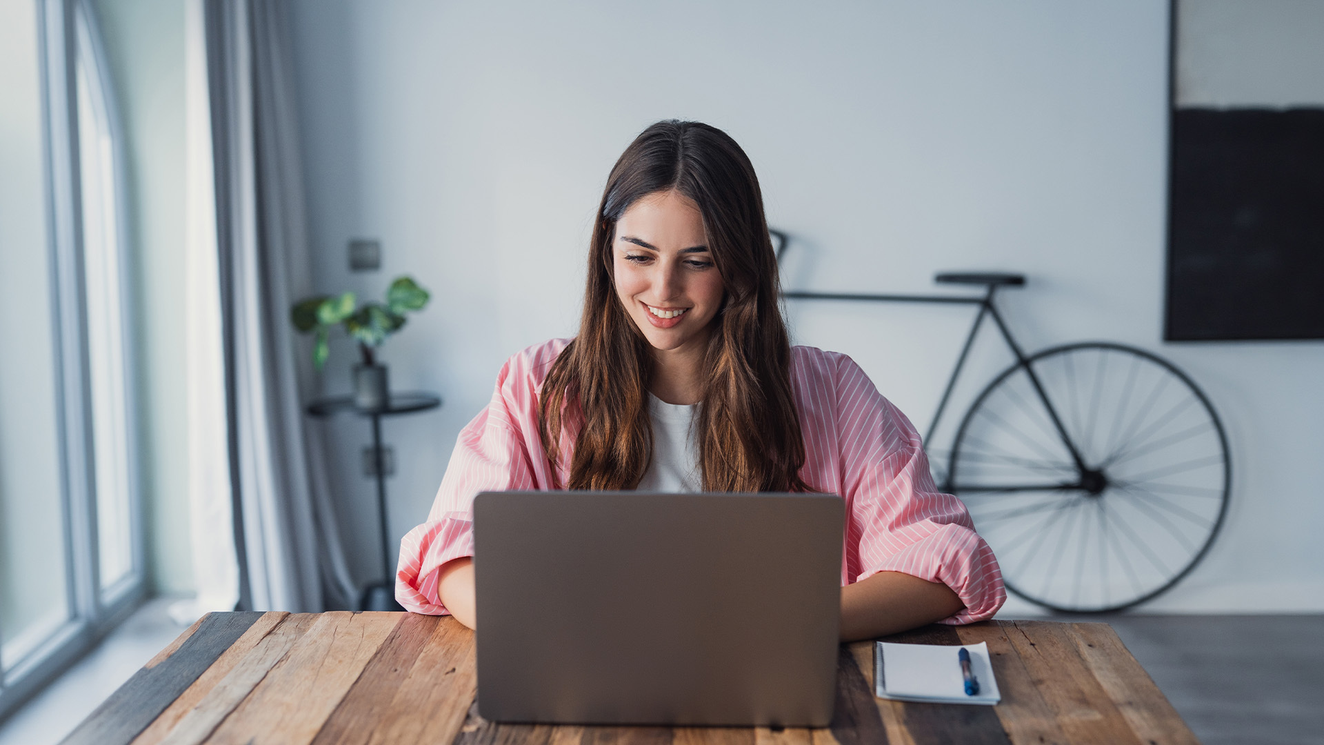 ragazza seduta in una scrivania che sorride guardando il computer davanti